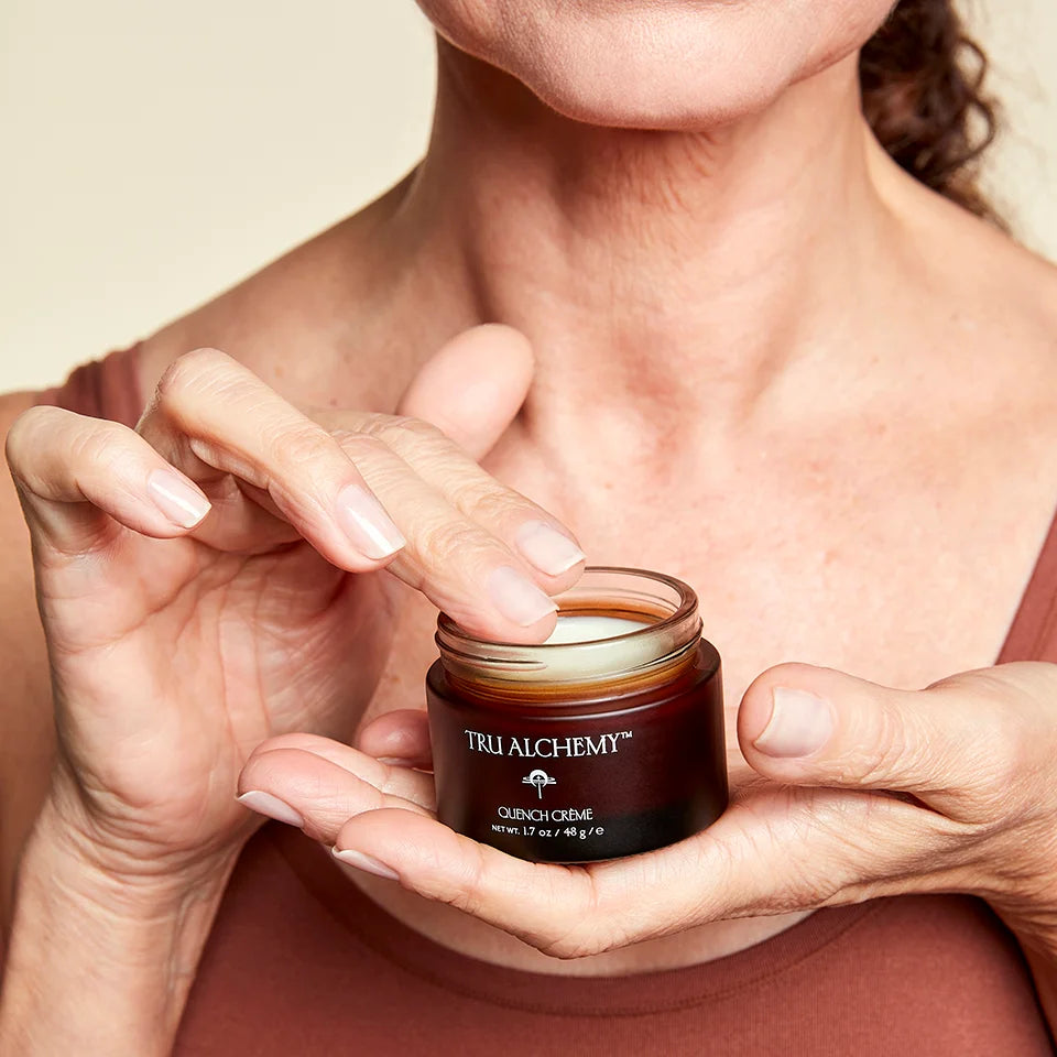 Close up of woman's hand holding a jar of Tru Alchemy's Quench Creme