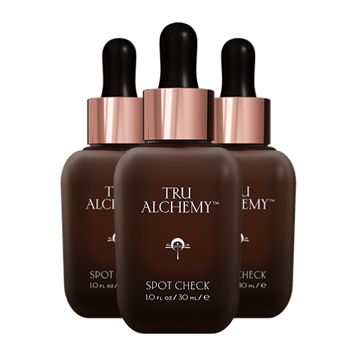 TruAlchemy Spot Check serum three bottles with rose gold dropper caps arranged in a triangle formation