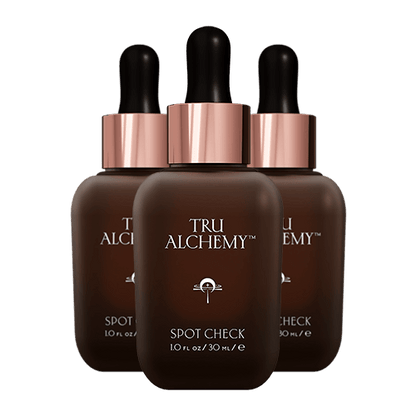 TruAlchemy Spot Check serum three bottles with rose gold dropper caps arranged in a triangle formation